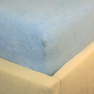 Prześcieradło frotte z gumką błękitne na rogu łóżka firmy TuliSen.