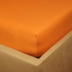 Prześcieradło jersey z gumką o kolorze zgaszonej pomarańczy na rogu łóżka.